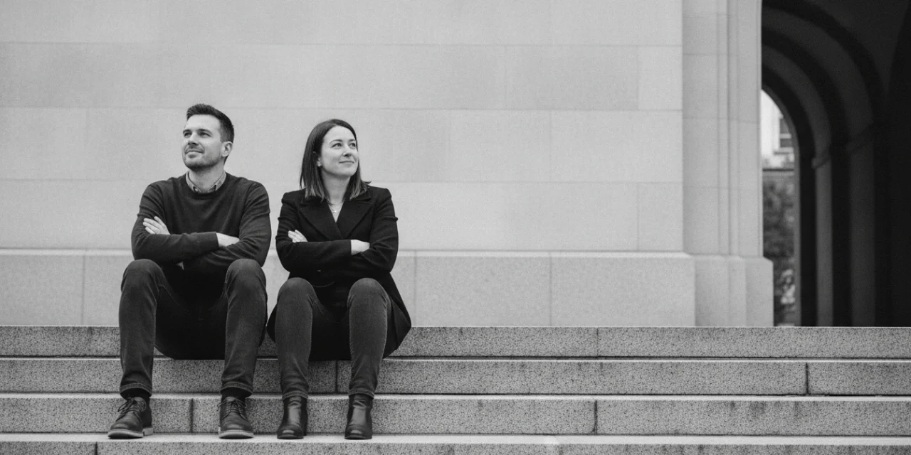 Identical relations: a man and a woman sit in mirrored, identical postures on stone steps