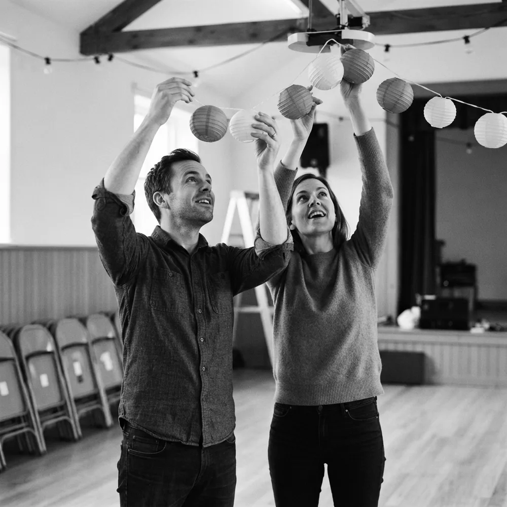 ENFJ personality type, the Herald: a man and a woman hang a garland of paper lanterns in a hall before an event